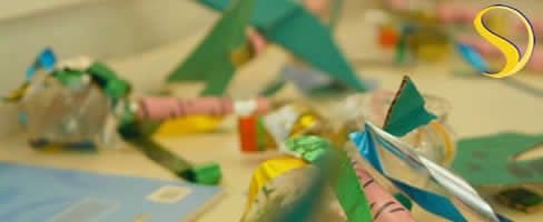 Trabalhos manuais coloridos de papel feitos por alunos sobre uma mesa